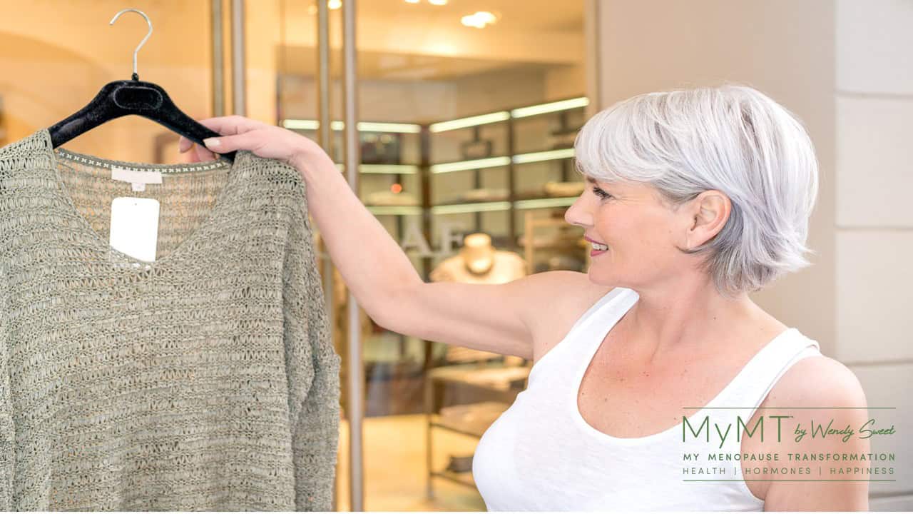 lady smiling holding a jumper from the shop clothes rack